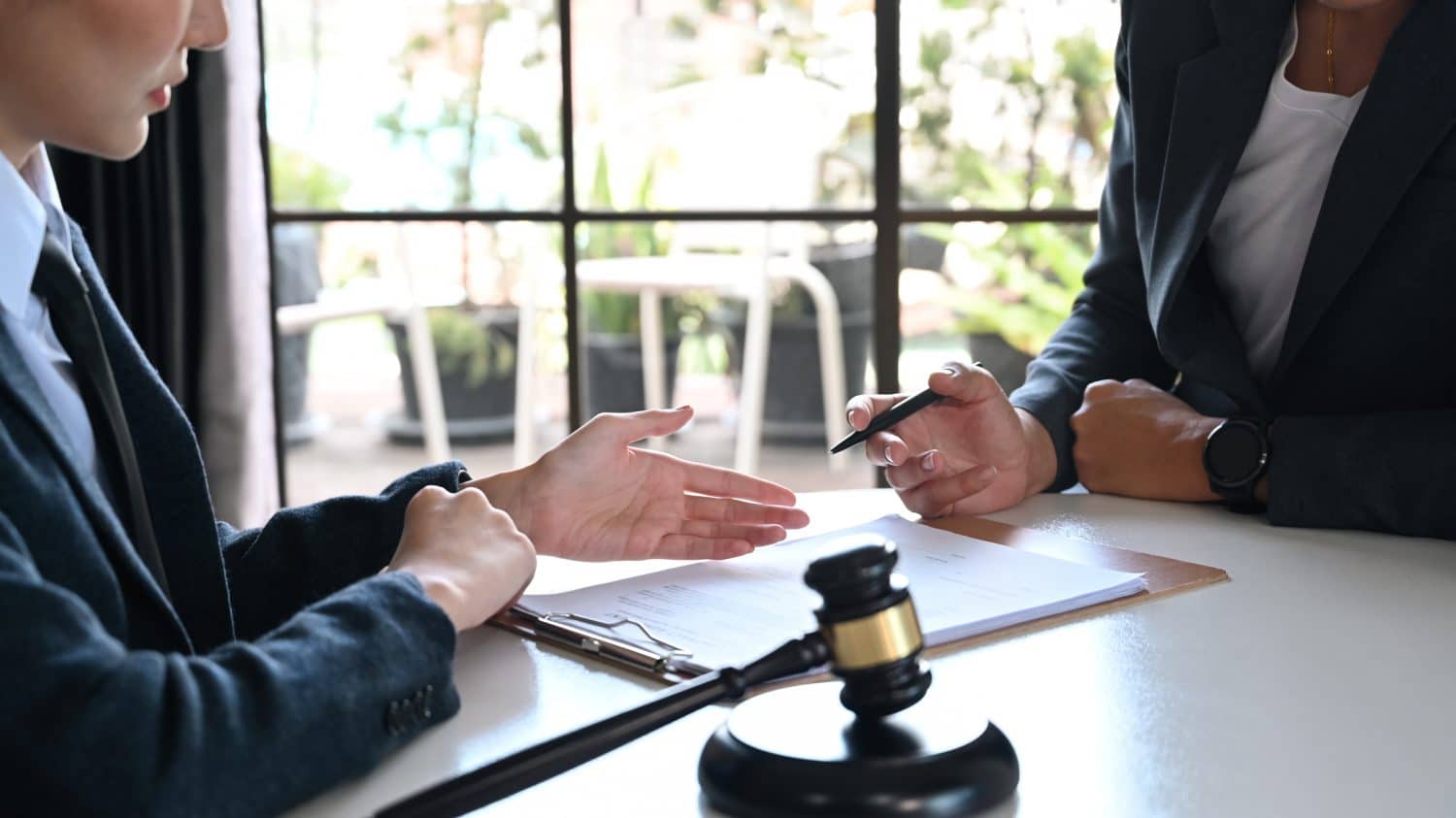 Personal injury attorneys gesture to one another while sitting at the negotiation table.