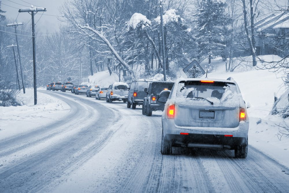 A line of cars driving on an icy road.