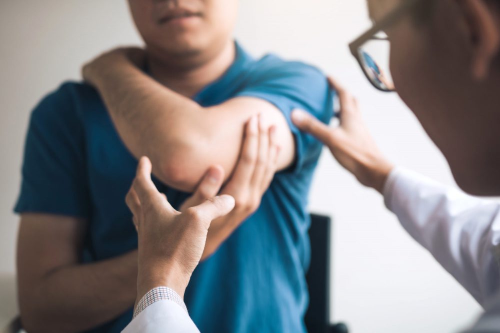 Physical therapist checking a patient’s elbow for injuries in a clinic office