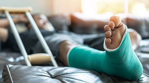 Injured man in cast laying down next to crutches