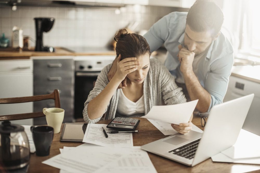 Distressed Couple Reviewing Bills At Their Table
