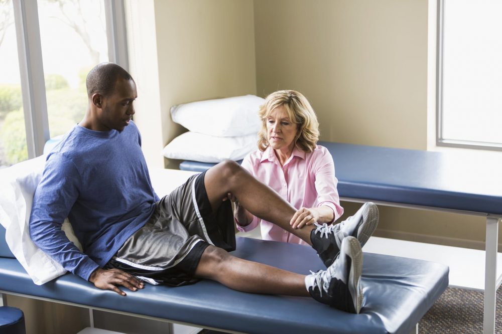 Man Having Leg Examined By Physical Therapist Stock Photo