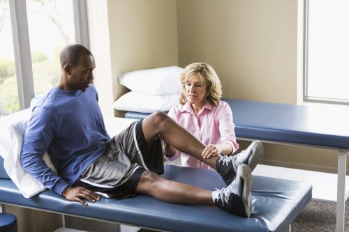 Man Having Leg Examined By Physical Therapist Stock Photo