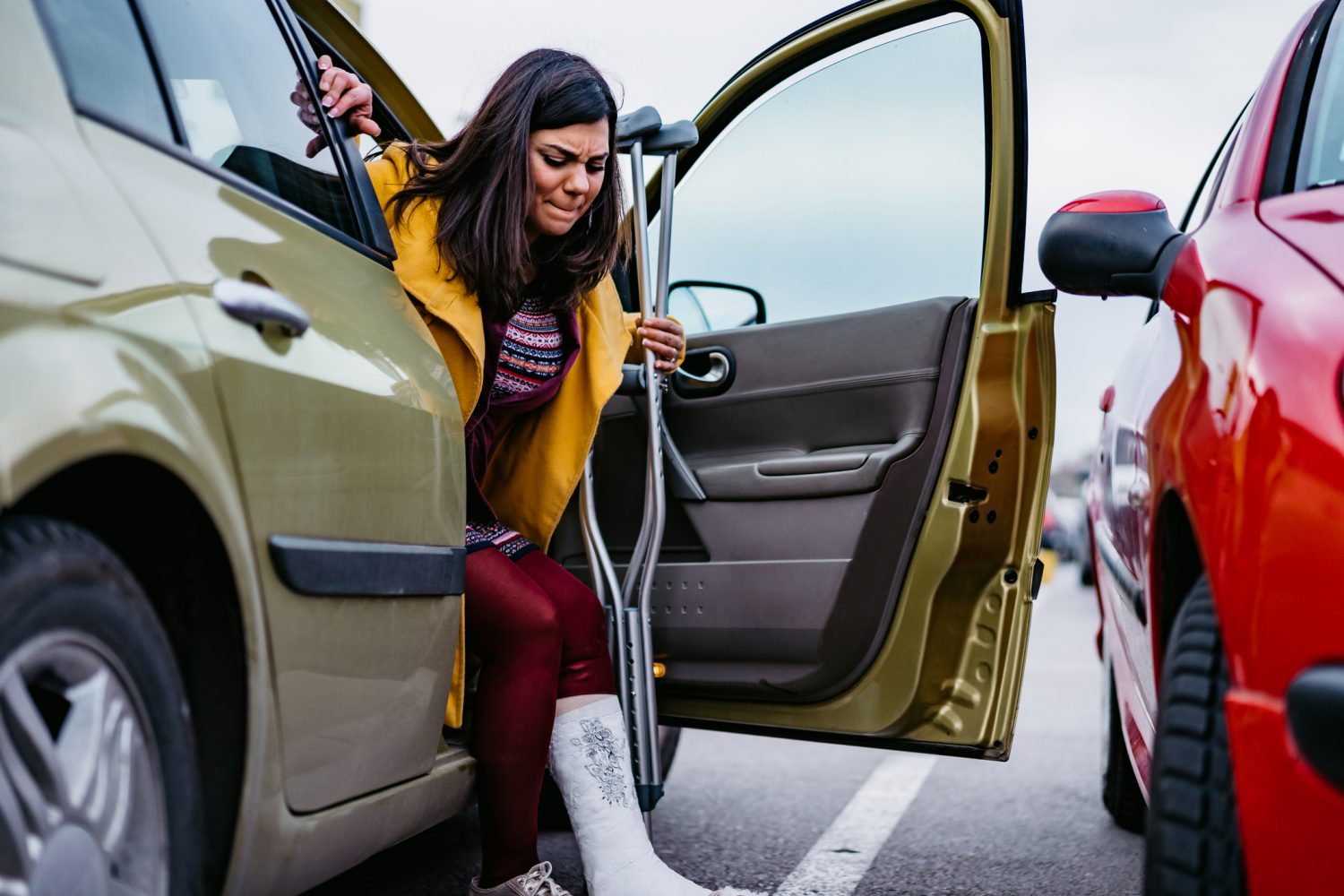 A woman with a broken leg getting out of her car.