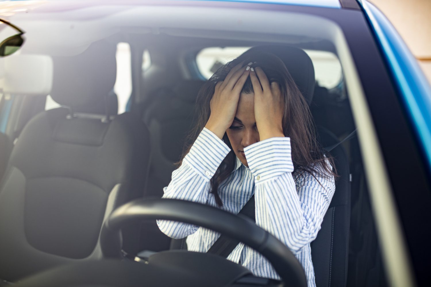 A woman in shock sitting in her car after a car accident.