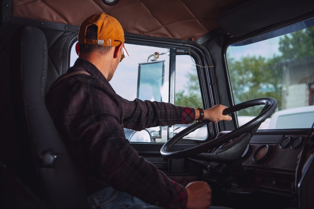 A truck driver sitting behind the wheel. 