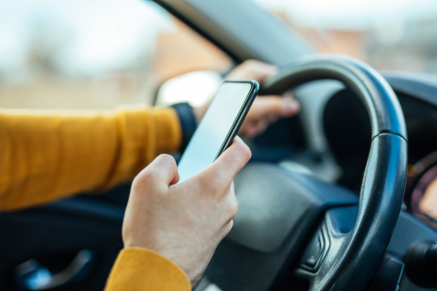 A distracted driver is using their phone at the wheel, risking a Bloomington car accident.