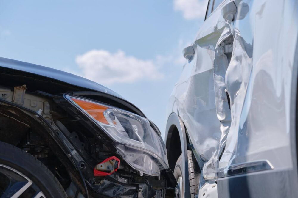 Close-up of a black sedan that has t-boned and dented a white sedan.