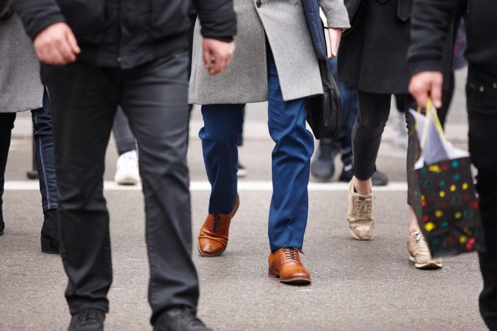 Waist-down view of a group of pedestrians walking across the street.
