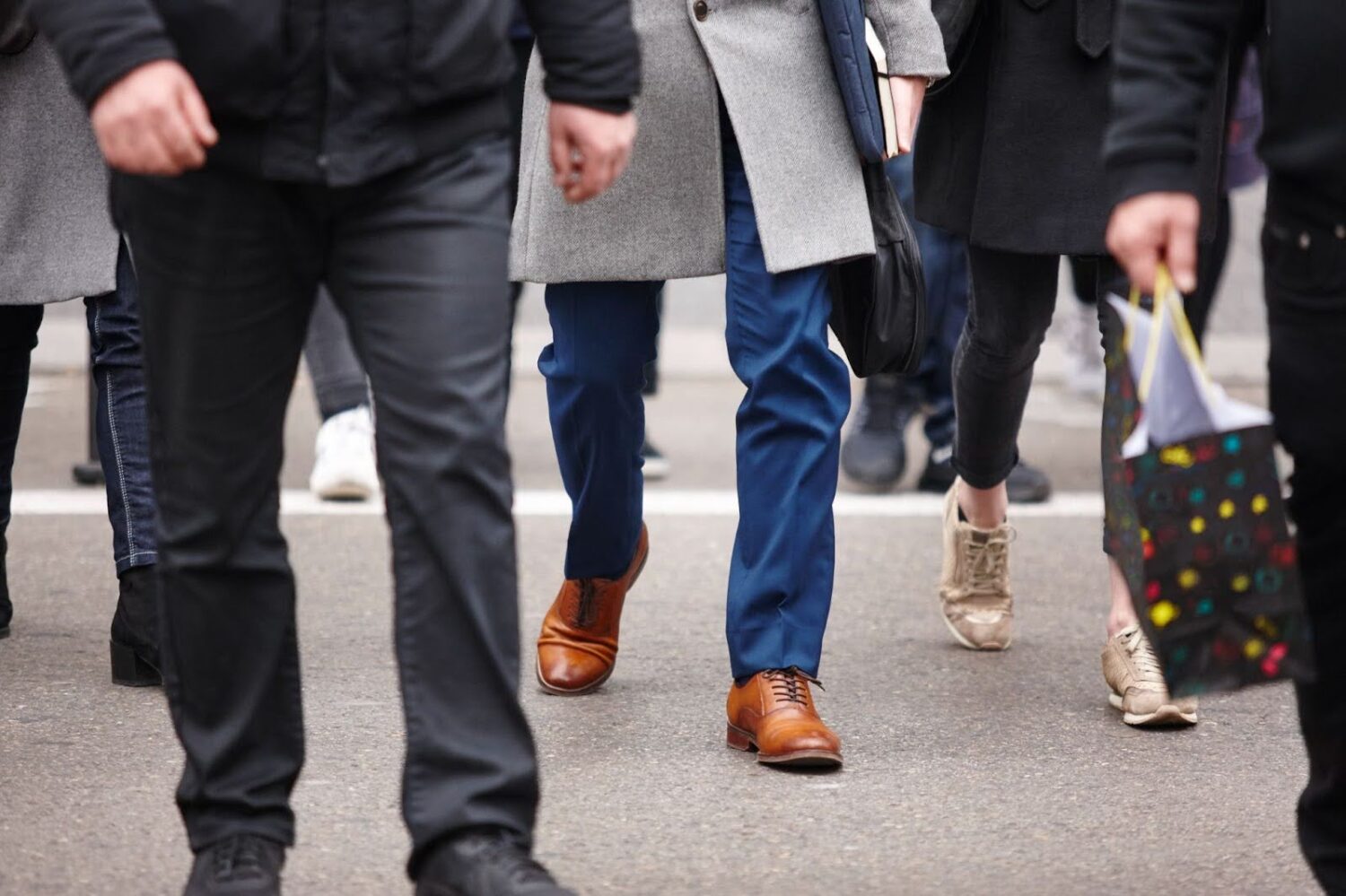Waist-down view of a group of pedestrians walking across the street.
