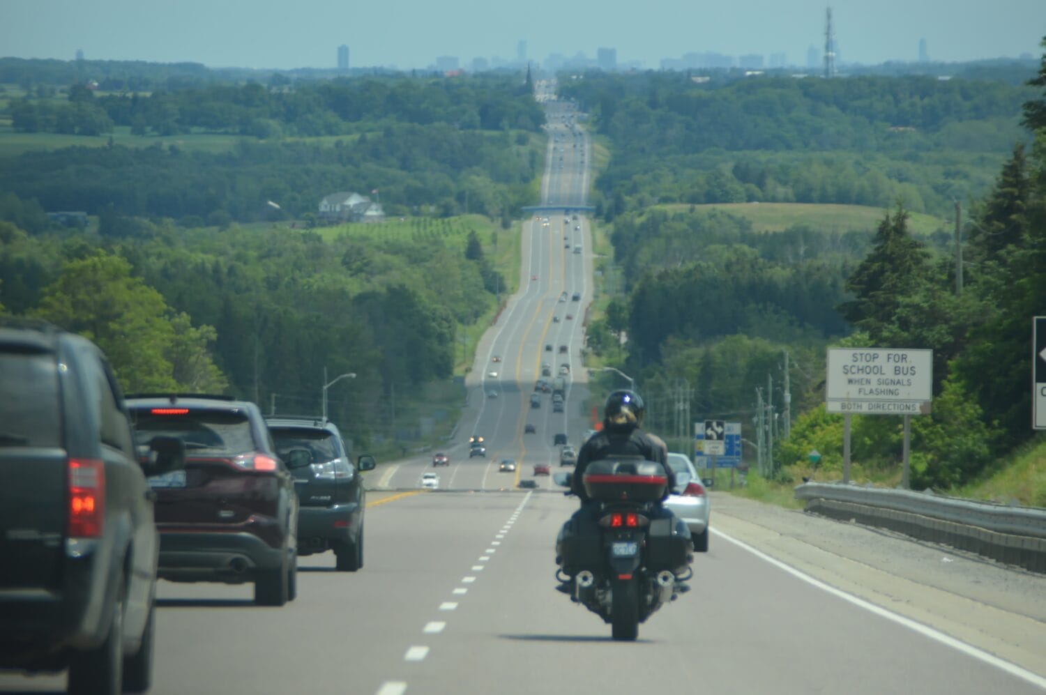 A motorcyclist shares a rural highway with other vehicles.