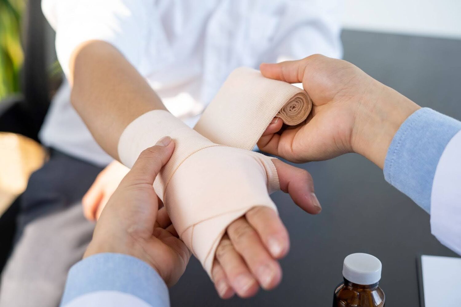 A doctor wraps the hand and wrist of an injured individual with an ACE bandage.