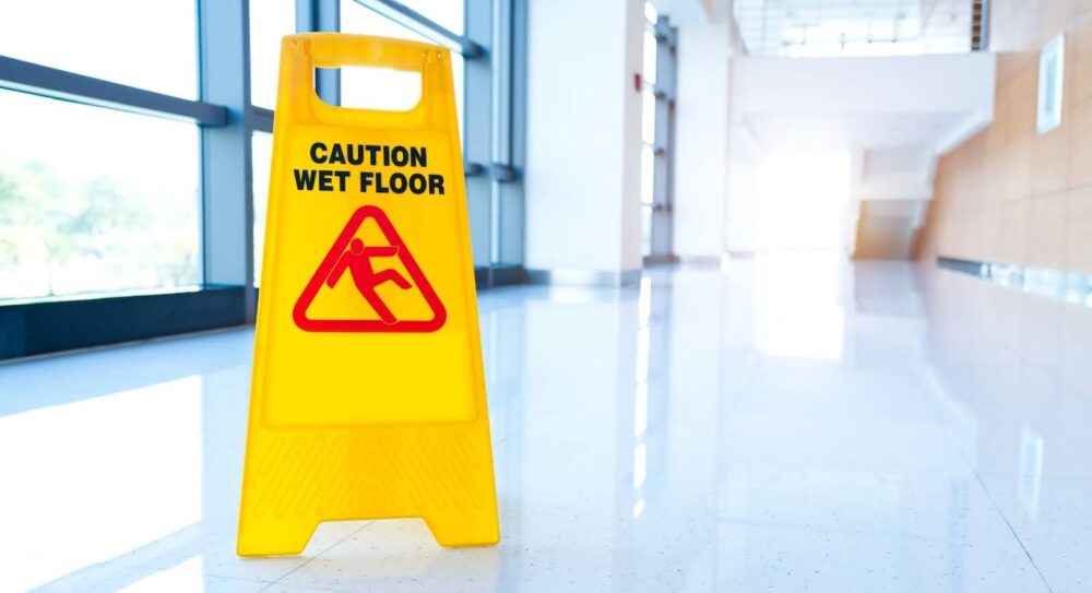 A bright yellow “Caution Wet Floor” sign placed in a well-lit hallway.