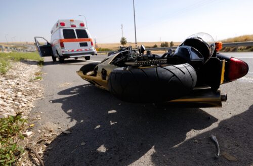 Motorcycle Wreck on the road with an ambulance seen in the background.