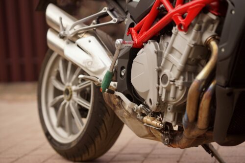 Close-up on the side of a motorcycle standing on brick pavement.