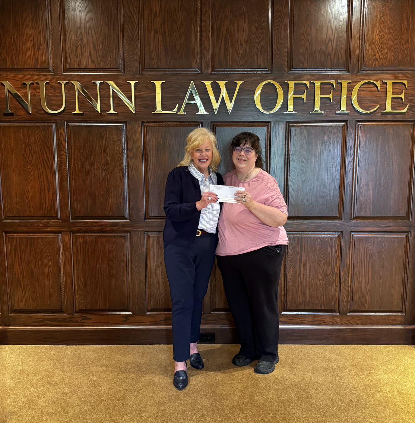 Attorney Vicky Nunn hands a representative from Pantry 279 a donation check.