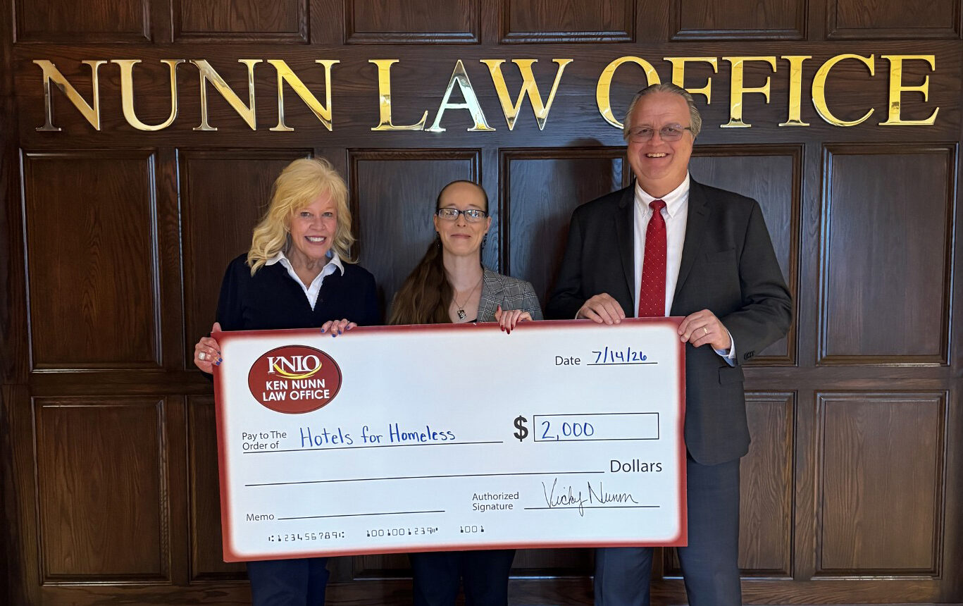 Attorneys Vicky Nunn and Dean Arnold with Katie Norris of Hotels for Homeless holding a donation check.