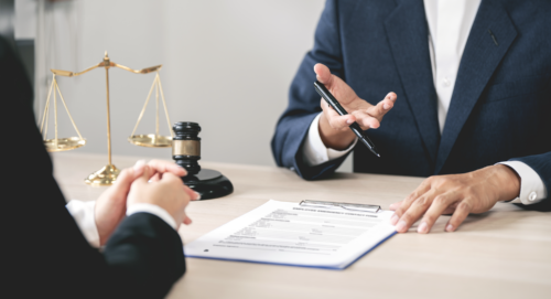 A lawyer talking with a client while reviewing paperwork.